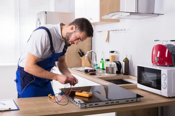 Technician testing a removed electric cooktop with diagnostic leads