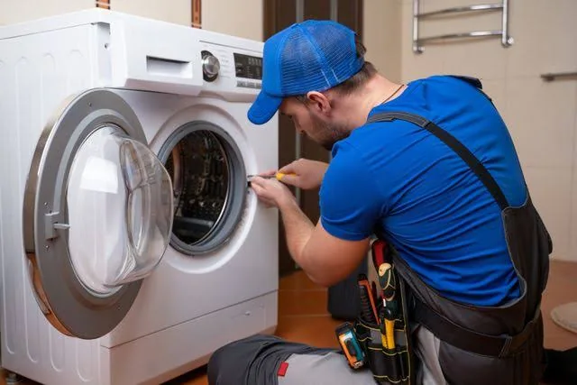 Technician servicing a front-loading laundry appliance