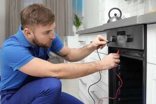 Technician testing an oven with red and black diagnostic leads